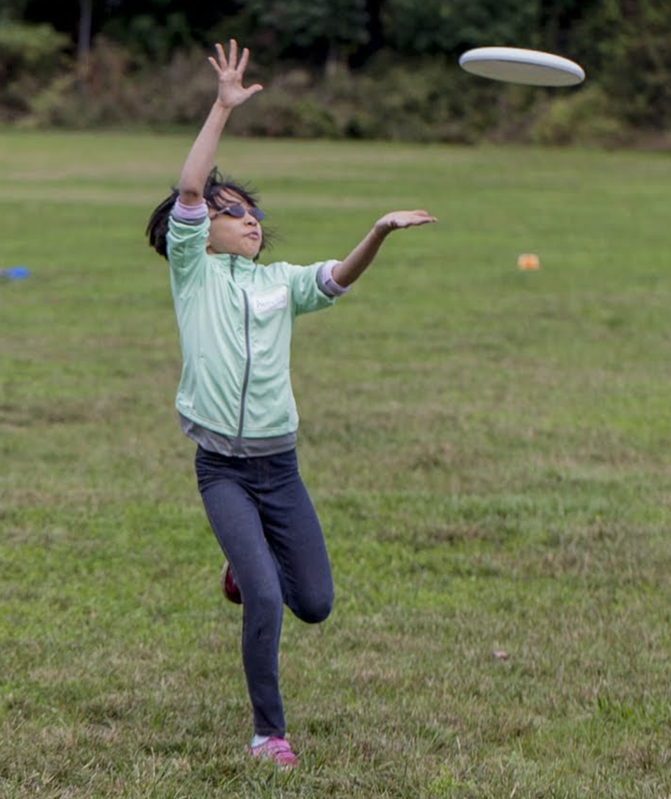 Fotografía de una niña que está atrapando un frisbee.