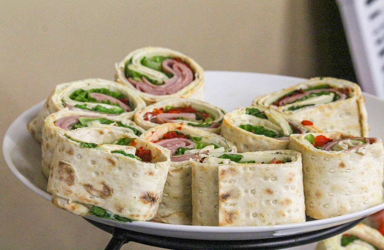 Many rolled-up sandwiches on a plate. 