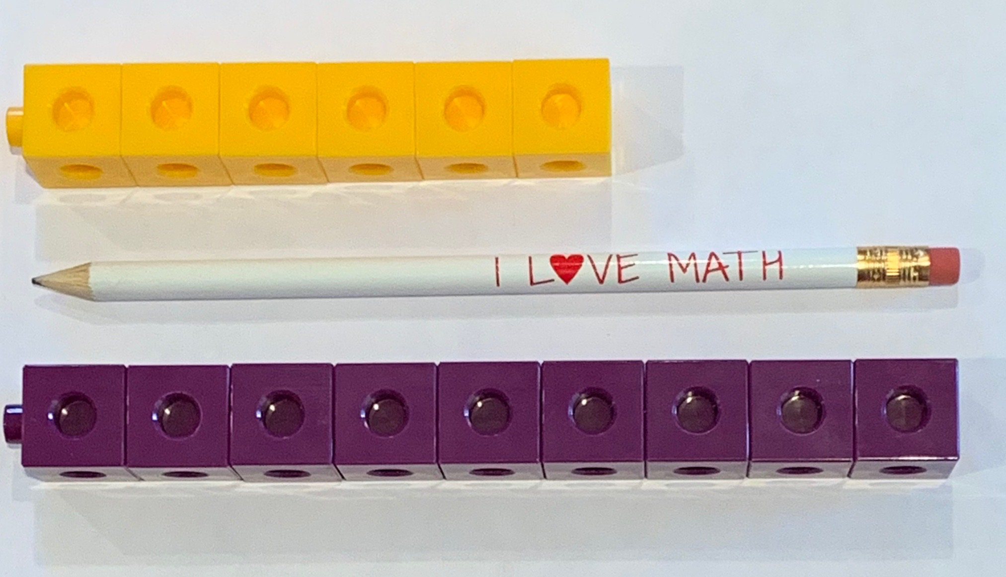 3 objects. Yellow tower, 6 connecting cubes. Purple tower, 9 connecting cubes. Pencil, same length as purple tower.