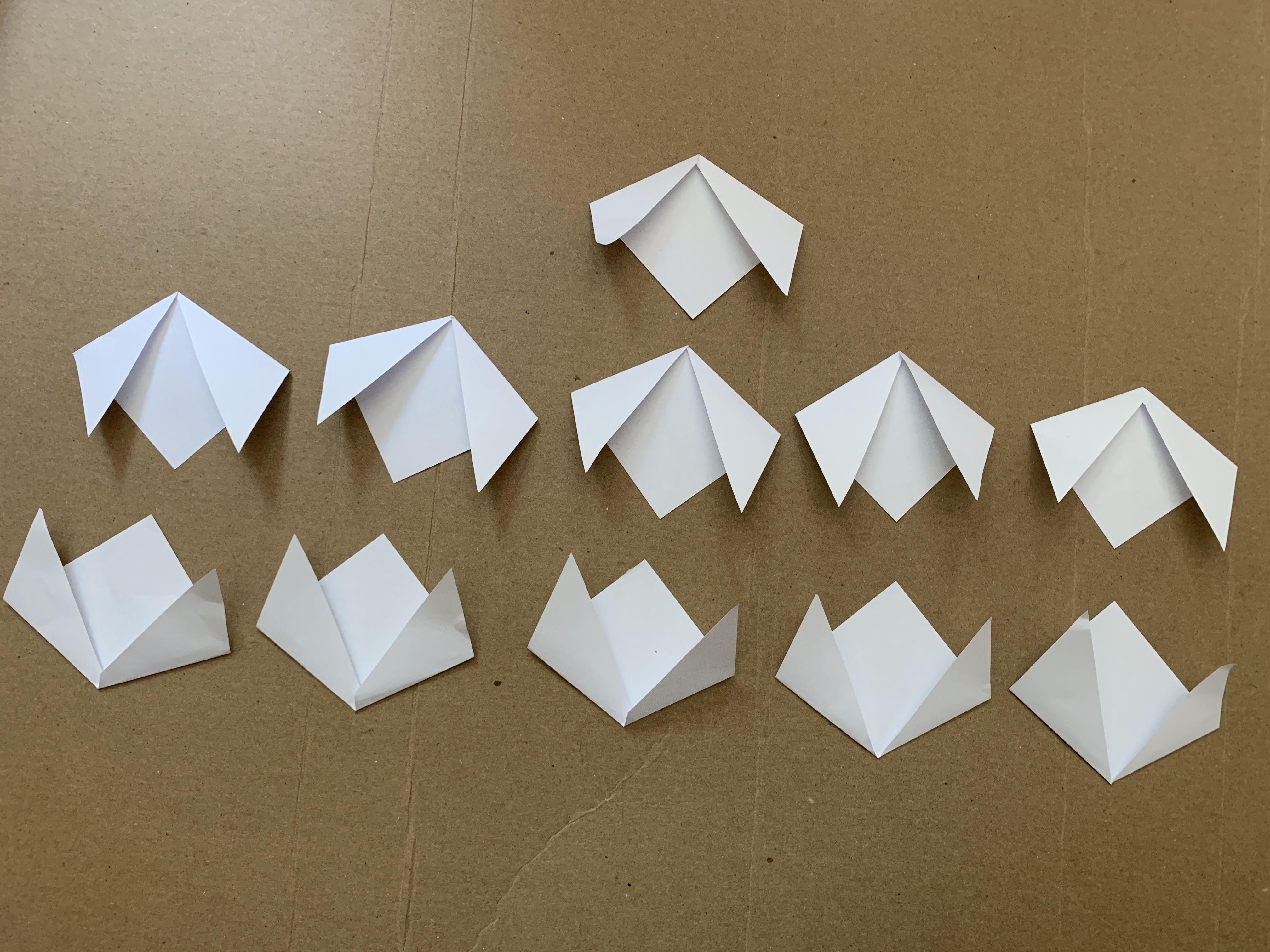 11 pieces of small paper, folded into the same shape.