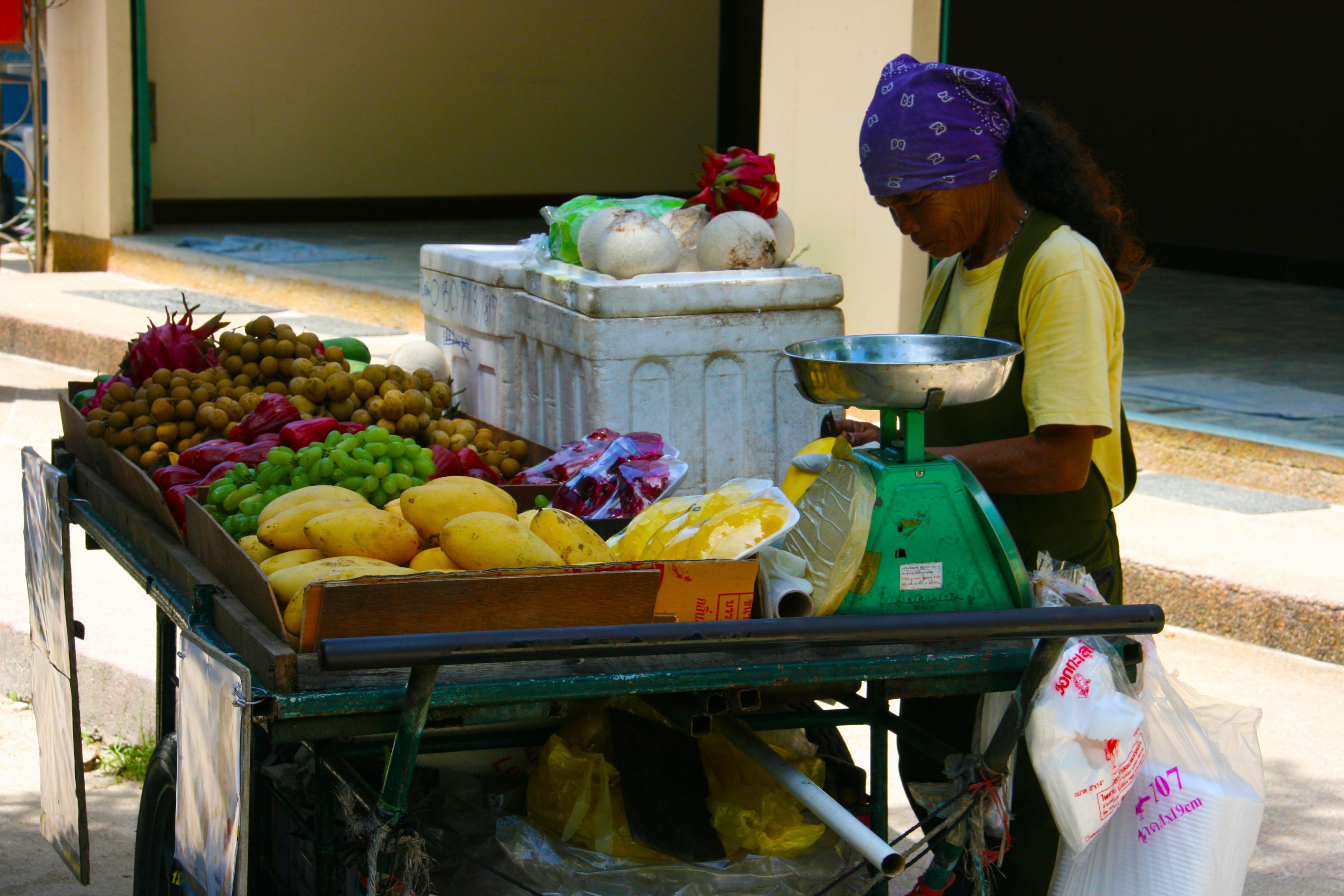 A woman working at a fruit and vegetable stand.