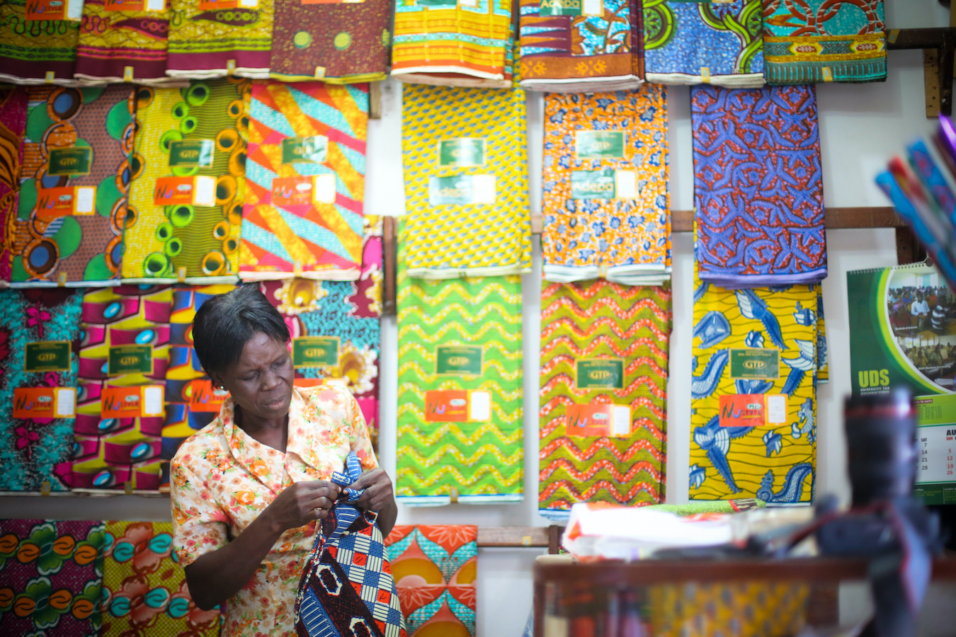 Fotografía de una mujer que está mirando telas con patrones de colores brillantes.