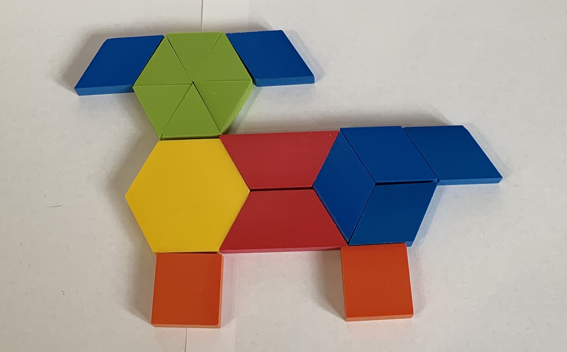Perro formado por fichas geométricas. 1 ficha amarilla, 2 rojas, 6 azules, 6 verdes y 2 anaranjadas.