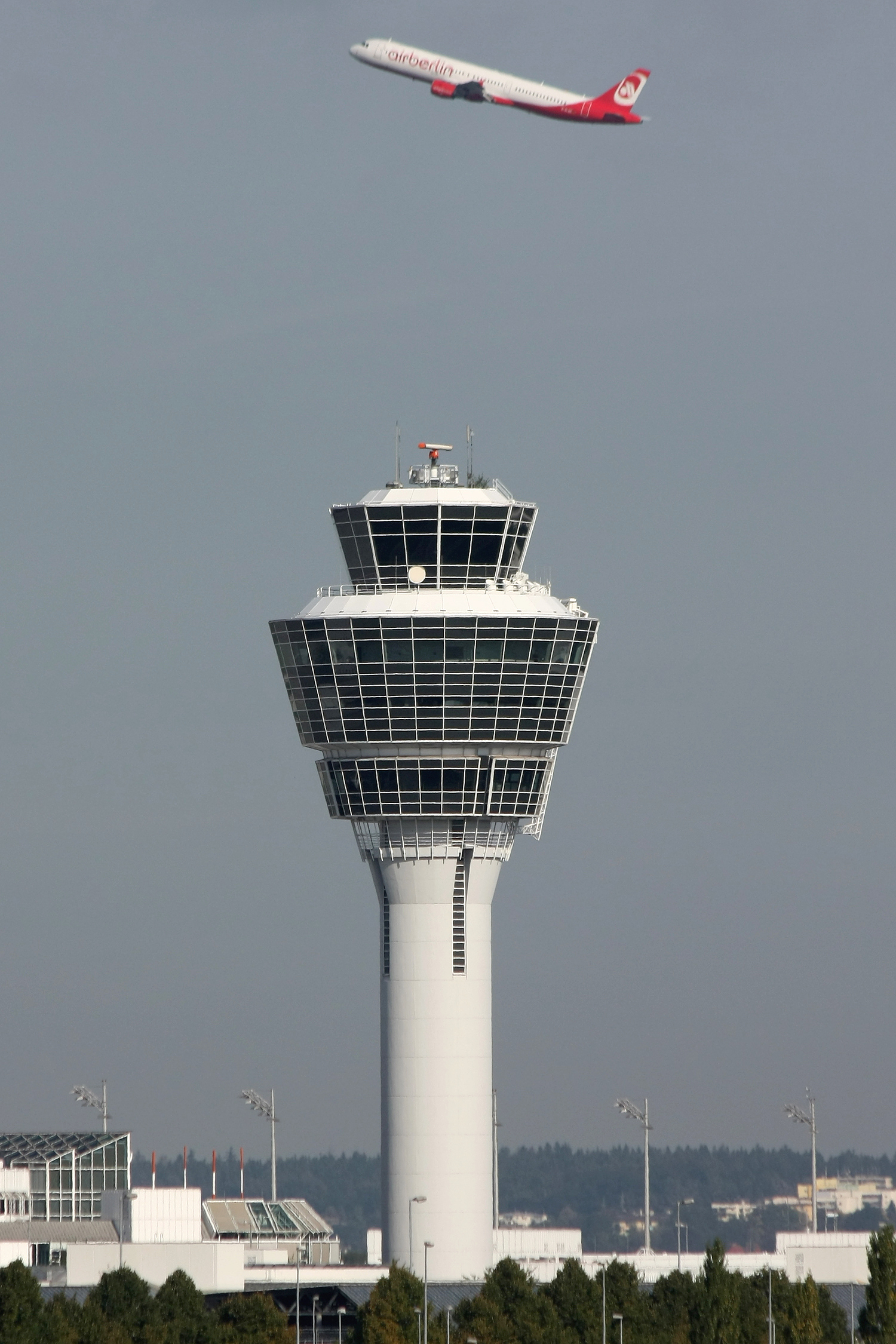 Fotografía de una torre de control de tráfico aéreo y de un avión después de haber despegado.