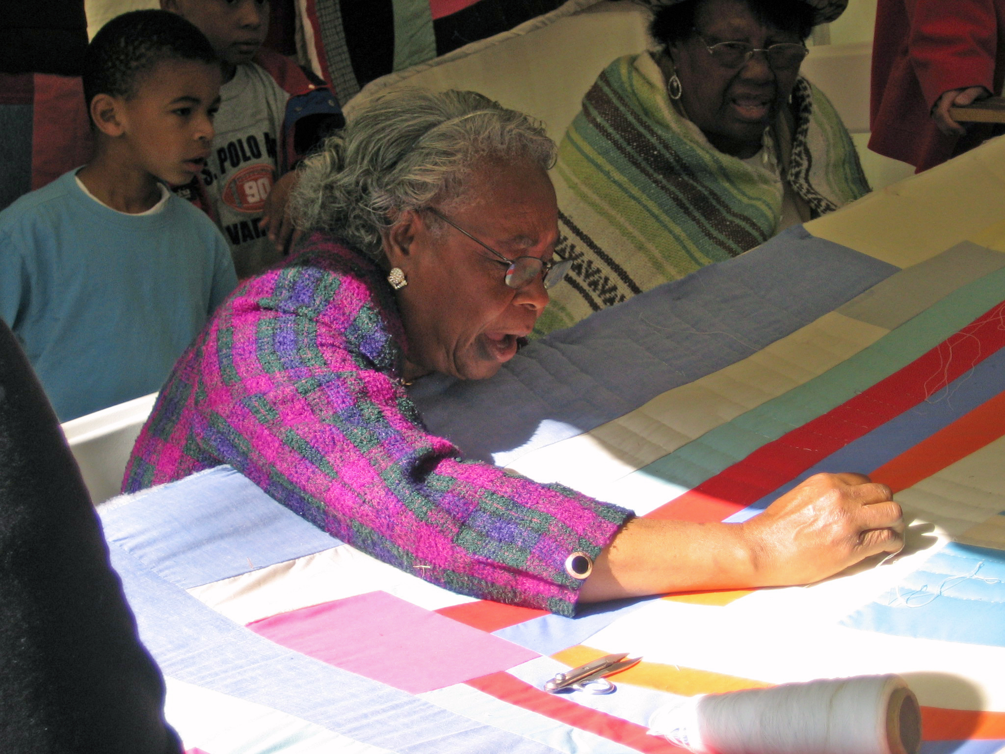a woman hand-sewing a quilt