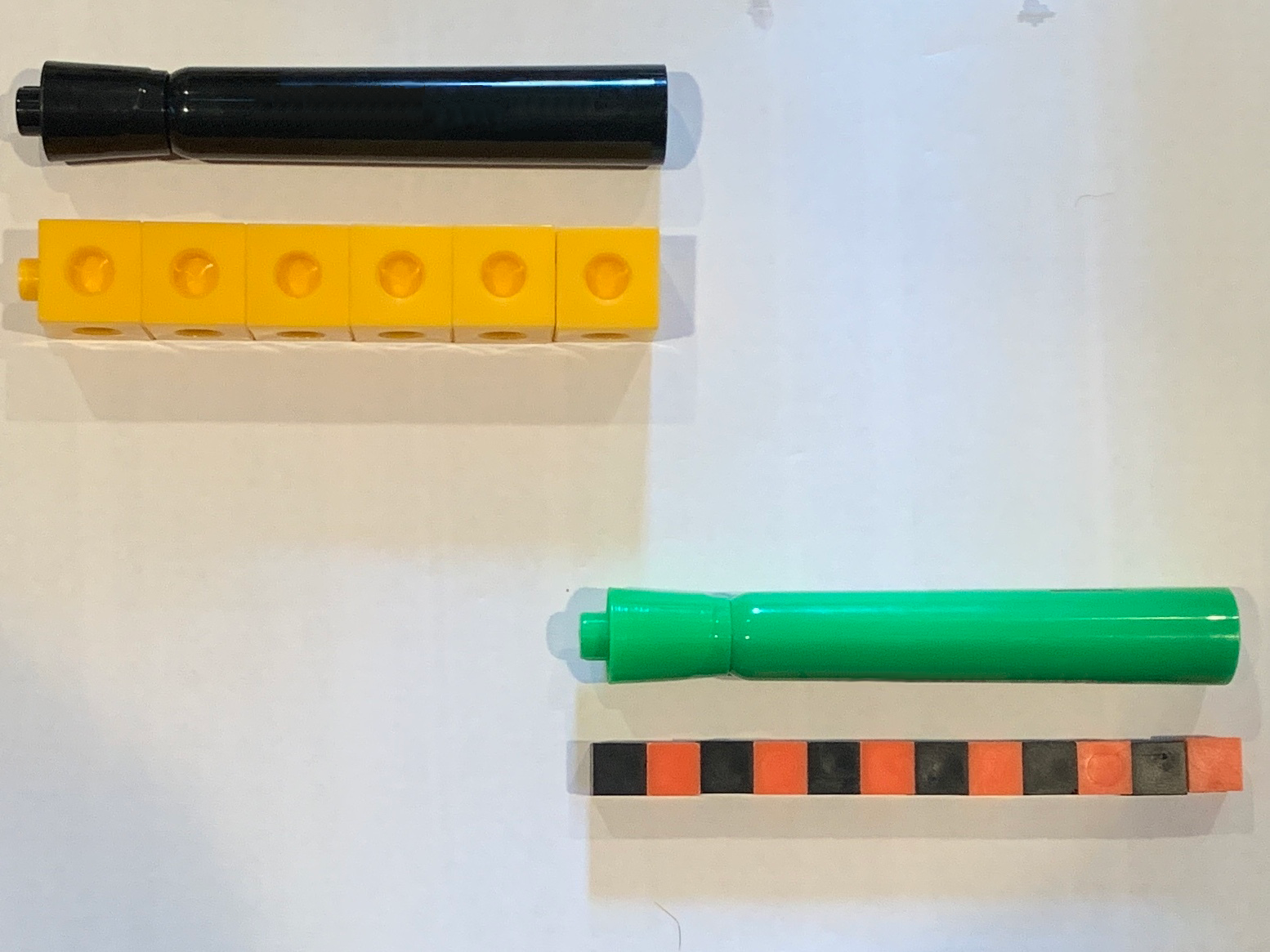 Markers with cubes below. Black marker, 6 connecting cubes. Green marker, 12 small cubes.