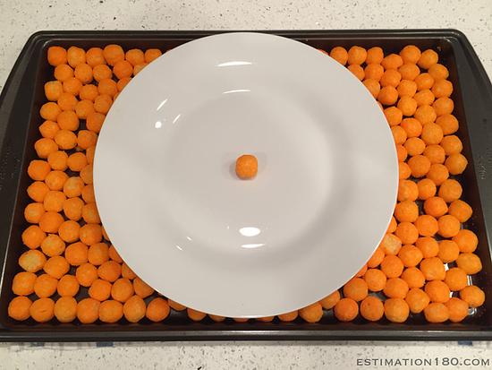 a playe with one cheese puff is shown surrounded by lost of other cheese puffs